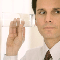 man in formal attire humorously listens through a glass, blending seriousness with whimsy.