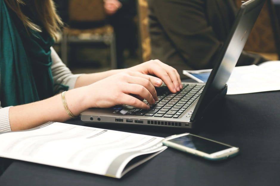 a woman typing on a laptop at a table