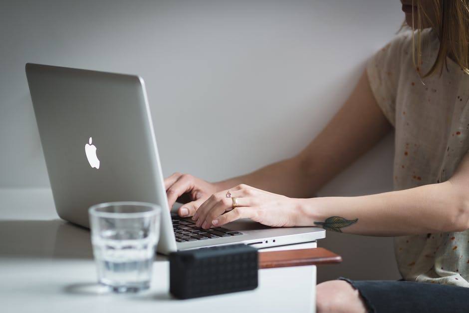 a person typing on a silver macbook in a tranquil and modern workspace.