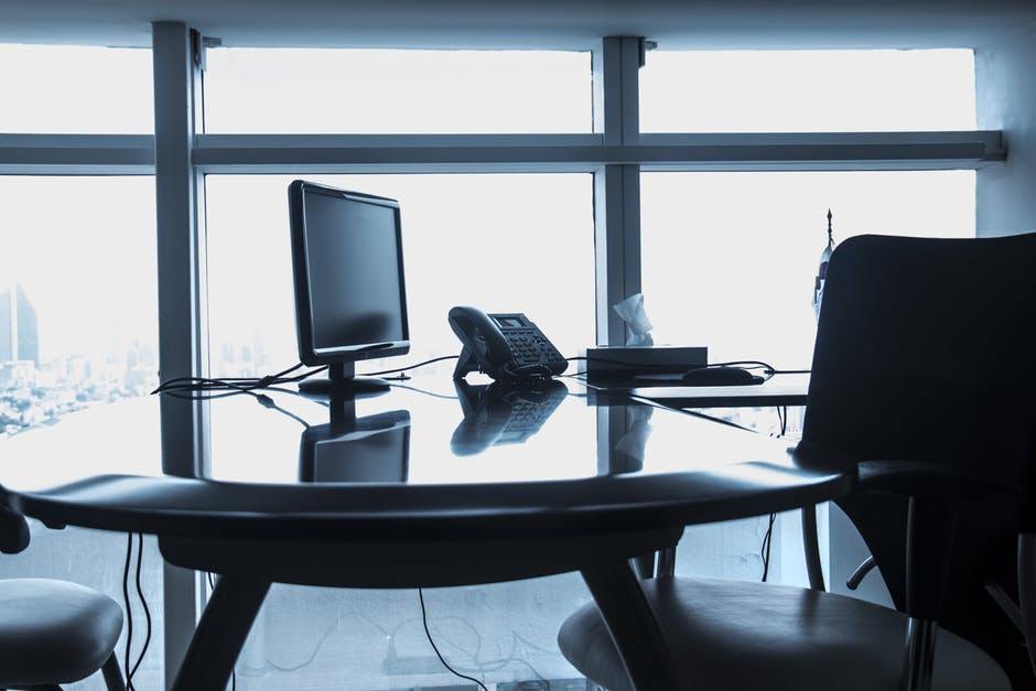 a black and white photo of a desk with a computer