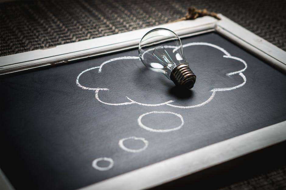 light bulb on black chalkboard with thought bubble, symbolizing creativity and brainstorming.