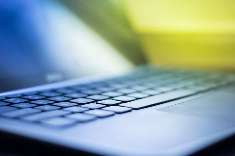 close-up of a sleek laptop keyboard against a vibrant blue and yellow background.