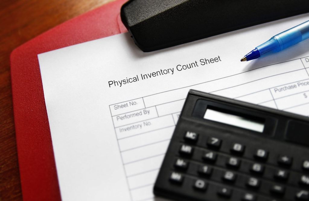 workspace essentials for efficient physical inventory management: count sheet, pen, and calculator.