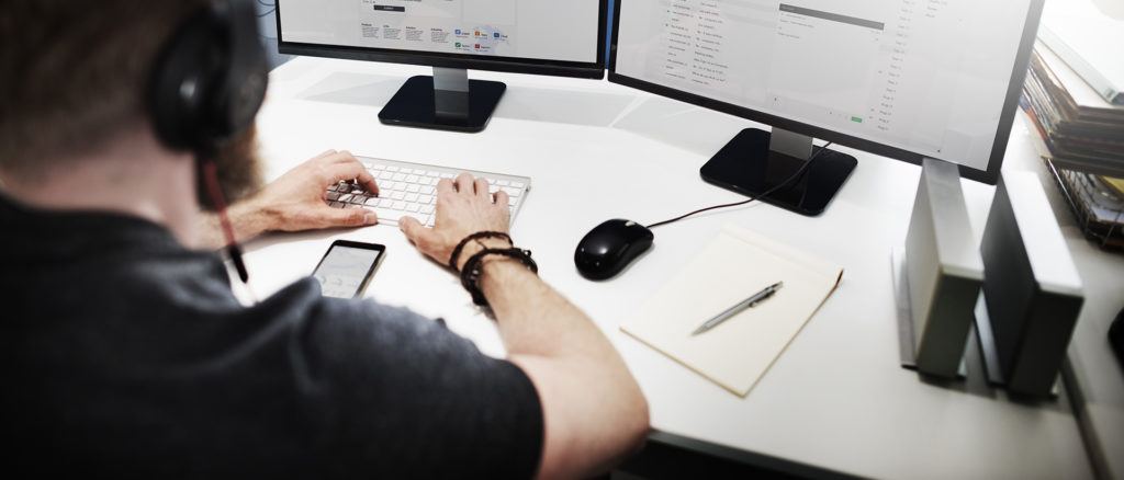 focused individual utilizing dual monitors in a modern, organized workspace for optimal productivity.