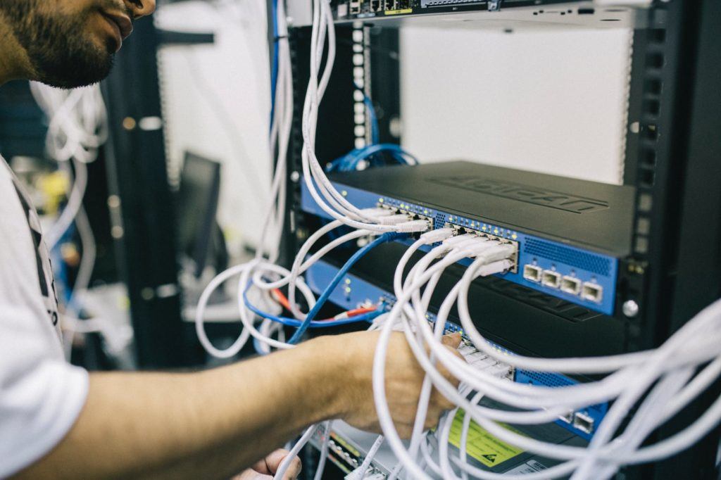 technician managing cables on a network switch in a modern data center.