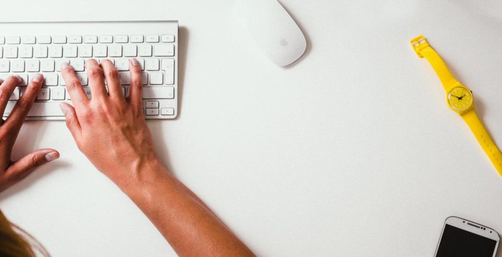 minimalist workspace featuring a woman typing on a stylish keyboard with tech accents.