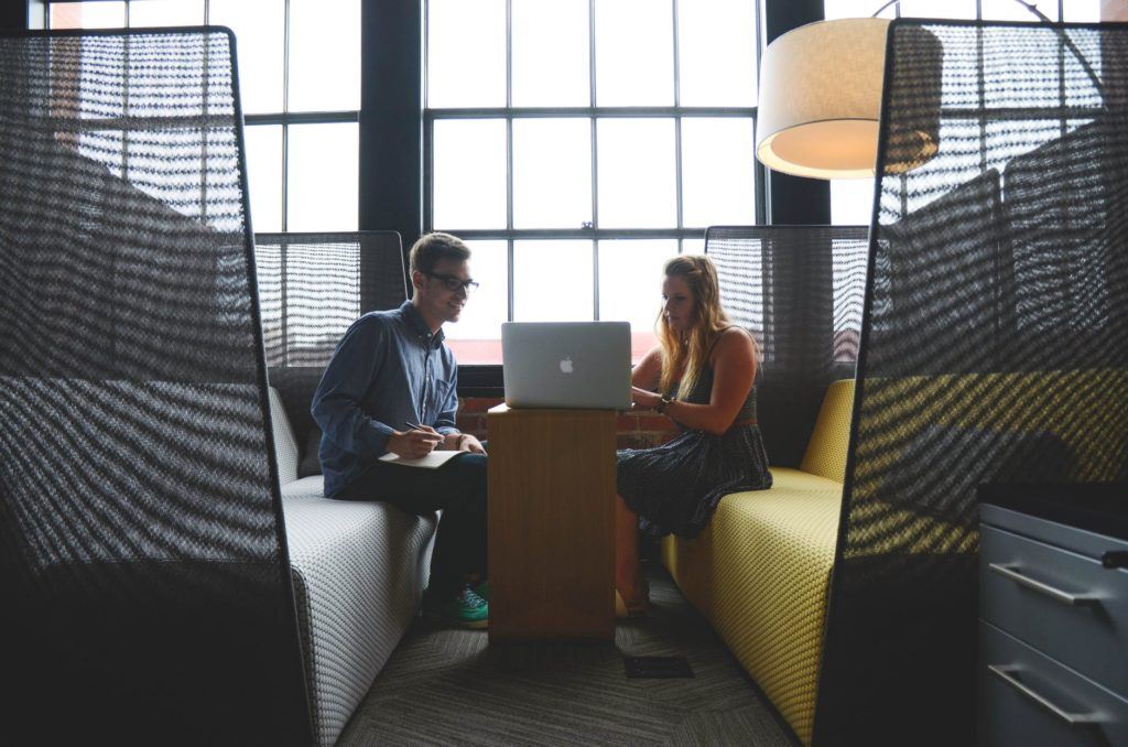 a man and a woman sitting at a table with a laptop