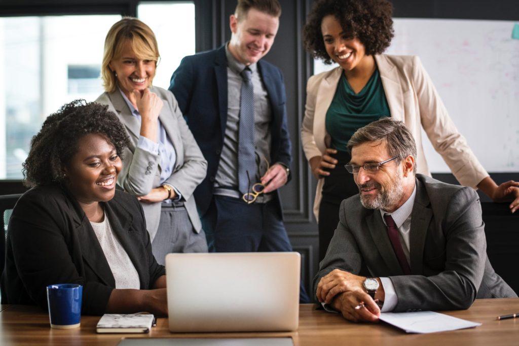 diverse team collaborating around a laptop in a bright, modern office space.