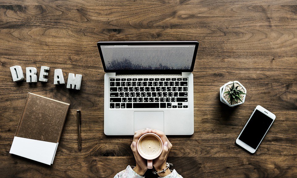 inviting workspace featuring a laptop, notebook, plant, and inspiring word dream.