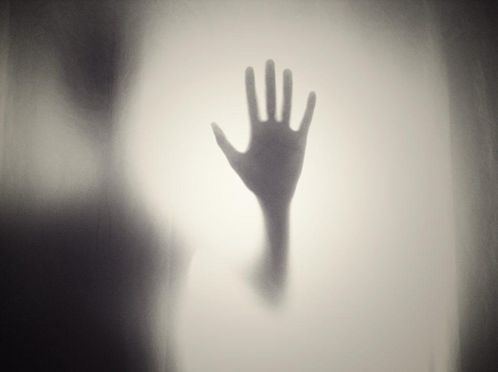 a silhouette of a hand reaching out of a foggy window