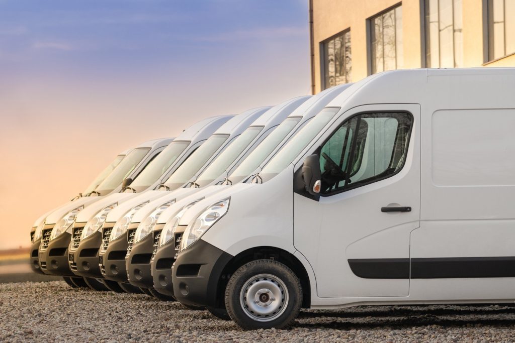 a row of white vans parked in front of a building