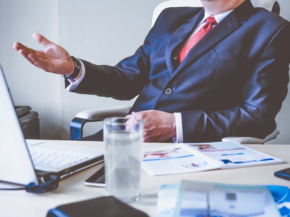 confident businessman discussing patch management at a modern desk with a laptop and documents.