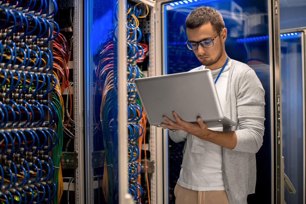 young it professional managing network infrastructure in a vibrant data center with colorful cables.