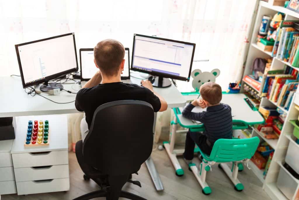 a boy and a boy sitting at a desk in front of computer monitors