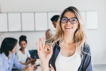 cheerful woman at the forefront, symbolizing positivity amidst a collaborative office team.