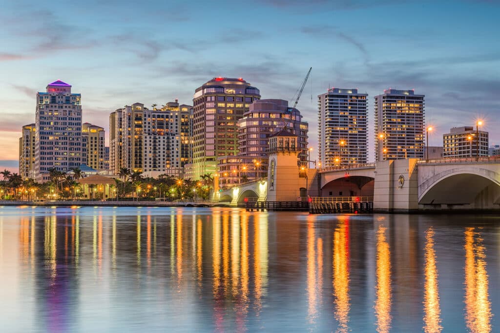 dusk skyline of west palm beach, reflecting vibrant colors in tranquil intracoastal waters.