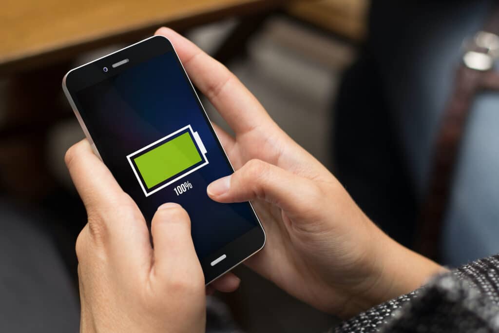 young girl engaging with smartphone displaying fully charged battery icon, symbolizing connectivity and energy.